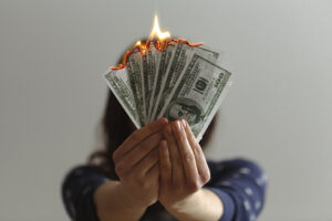 A woman holding burning 100 dollar bills