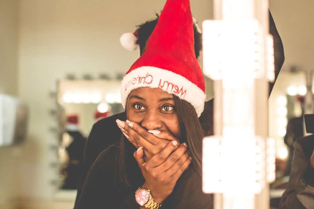 african american woman wearing santa's cap covering her mouth with both hands